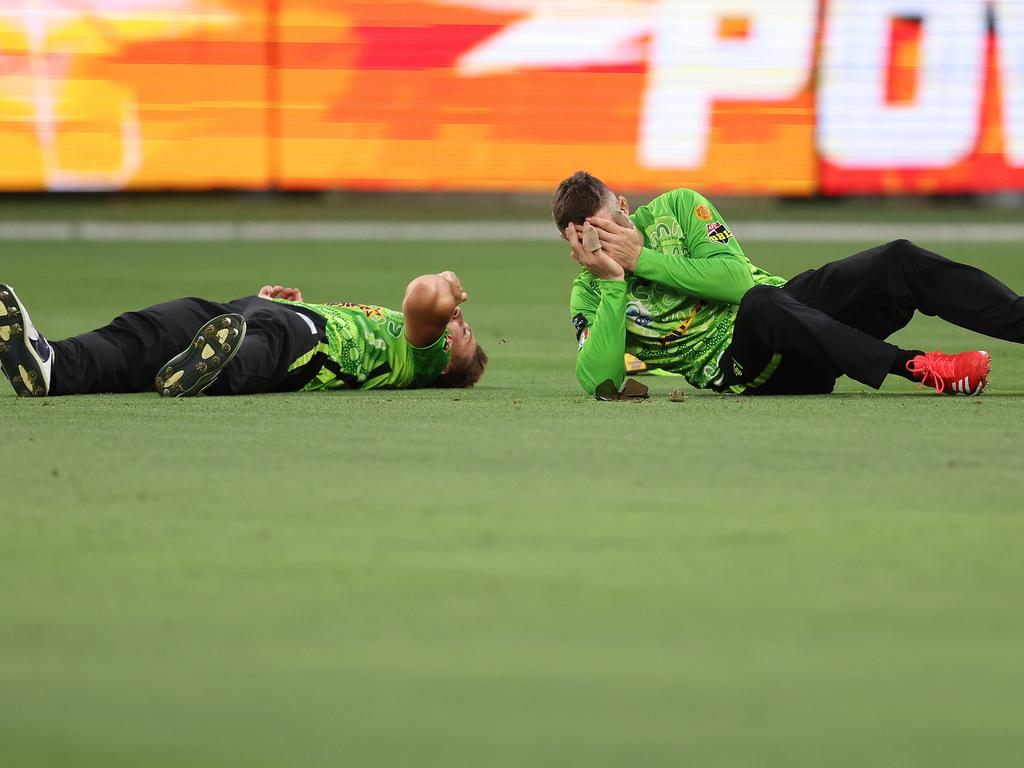 Both players lie prone on the turf.