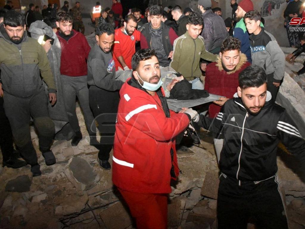 Rescuers carry a person on a stretcher and work at the site of a collapsed building, following an earthquake, in Hama, Syria. Picture: Reuters/SANA/Handout