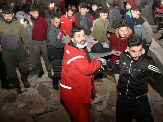 Rescuers carry a person on a stretcher and work at the site of a collapsed building, following an earthquake, in Hama, Syria. Picture: Reuters/SANA/Handout