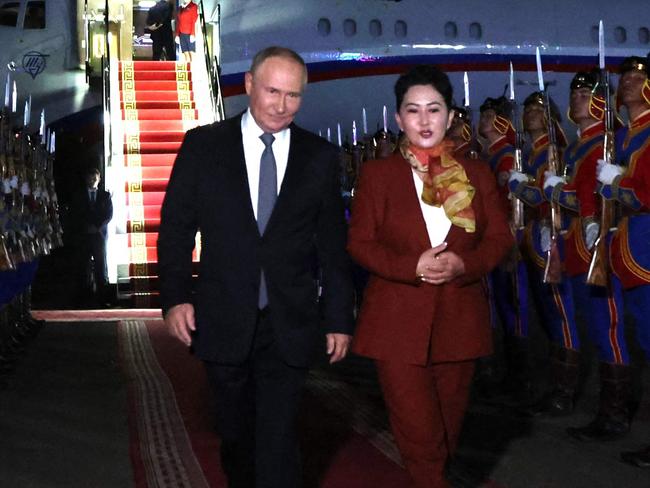 In this pool photograph distributed by the Russian state agency Sputnik, Russia's President Vladimir Putin, accompanied by Battsetseg Batmunkh, Mongolia's Minister of Foreign Affairs, walks past honour guards upon arrival at the airport in Ulaanbaatar on September 2, 2024. (Photo by Natalia Gubernatorova / POOL / AFP)