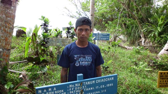 Hla Phyo stands next to a grave marker of a man he helped bury, a Burmese fisherman slave who died on a fishing boat, at a cemetery in Benjina, Indonesia. Phyo, a former slave, said conditions on the Thai-run trawlers were horrific. He said some men died after jumping into the water to wrestle with the giant, swollen nets.