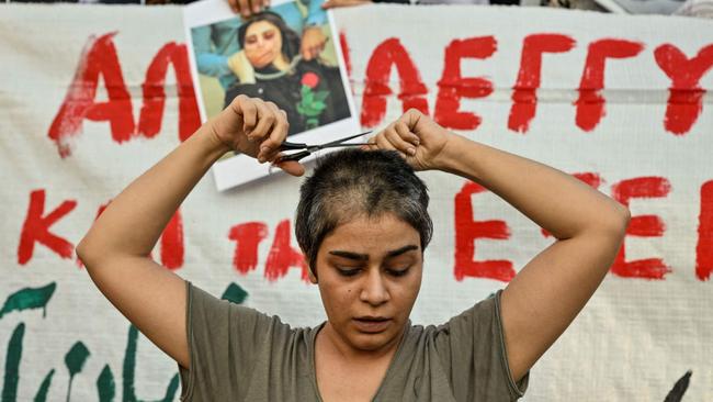 Eli, an Iranian refugee woman living in Greece cuts her hair during a demonstration by Iranians living in Athens. Picture: Louisa Goulimaki/AFP