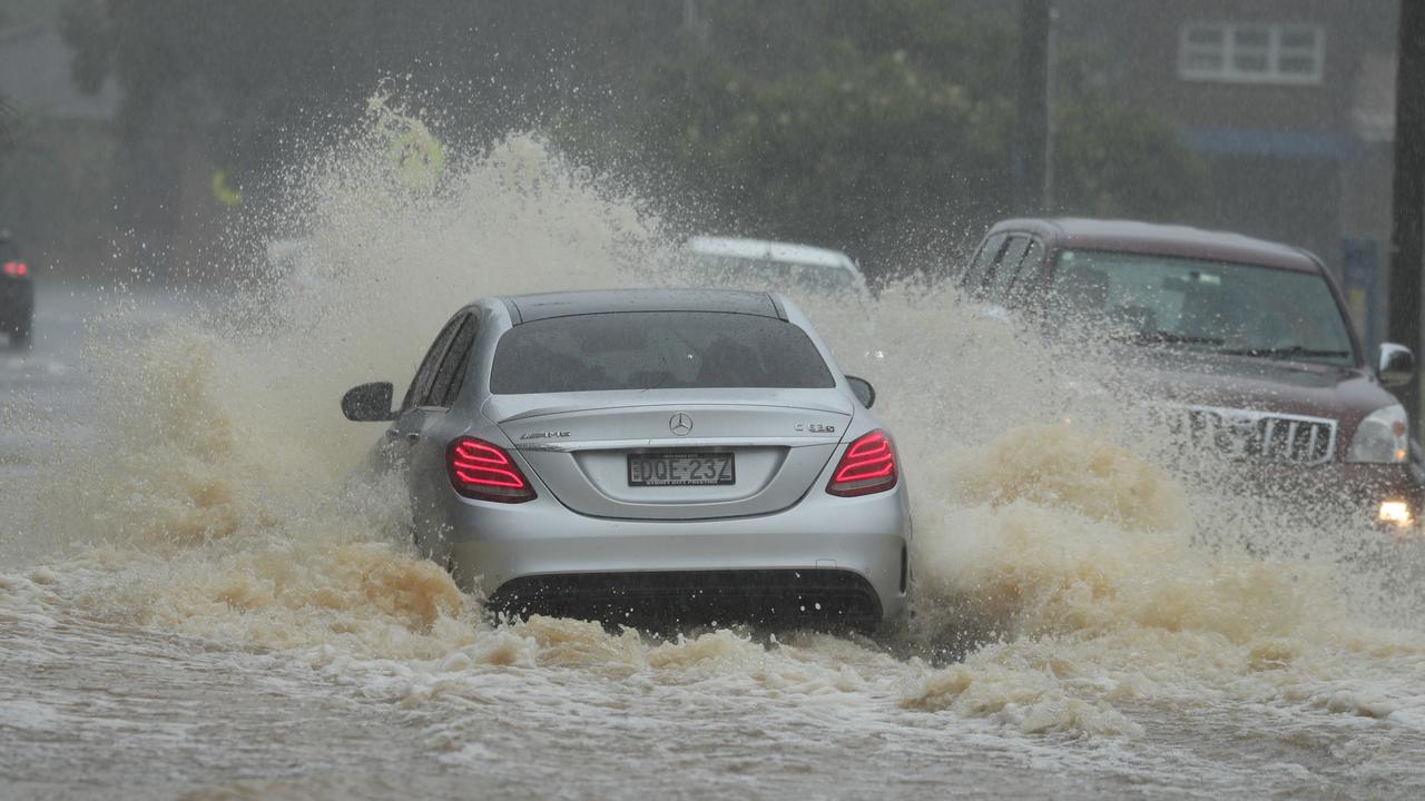 Cars tackle flood waters on Sydney’s northern beaches on Sunday. Picture: John Grainger