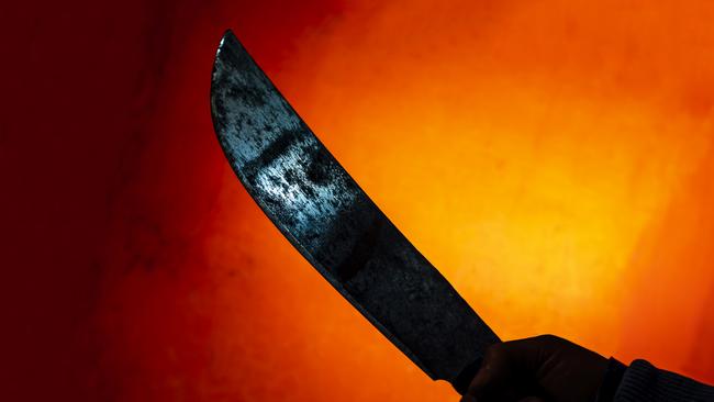 hand with scary machete with blue blade reflection in the darkness