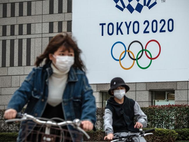 People cycle past a banner for the Tokyo Olympics in Tokyo, Japan. Picture: Getty Images