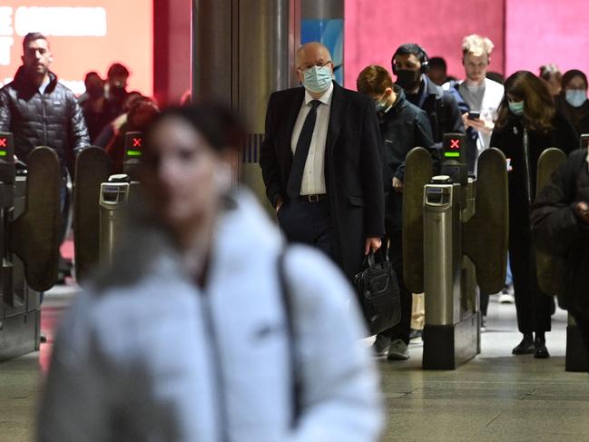 Commuters, with and without face coverings, walk out of a tube station in central London on January 27, 2022. Picture: AFP