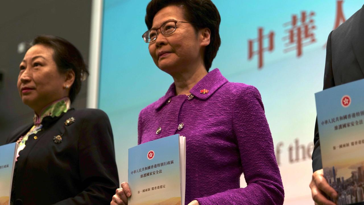 Hong Kong's Chief Executive Carrie Lam with Justice Secretary Teresa Cheng (left) while holding copies of the new national security law. Picture: Daniel SUEN / AFP.