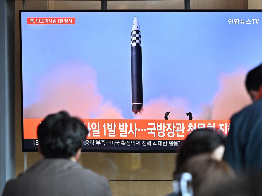 People watching a television screen showing a news broadcast with file footage of a North Korean missile test, at a railway station in Seoul. Picture: AFP