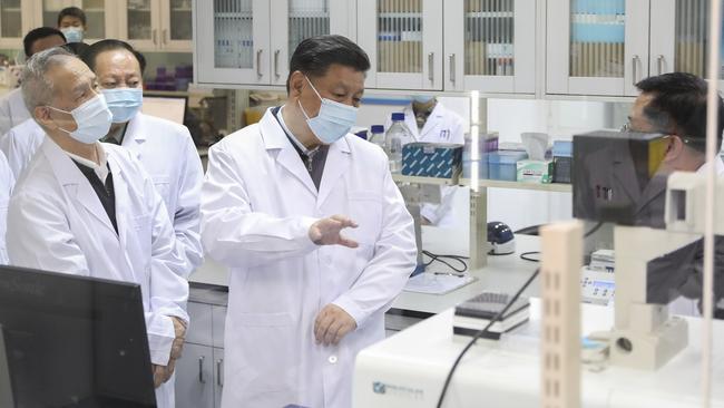 Chinese President Xi Jinping, centre, wearing a protective face mask, talks to a medical staff member during his visit to the Academy of Military Medical Sciences in Beijing.