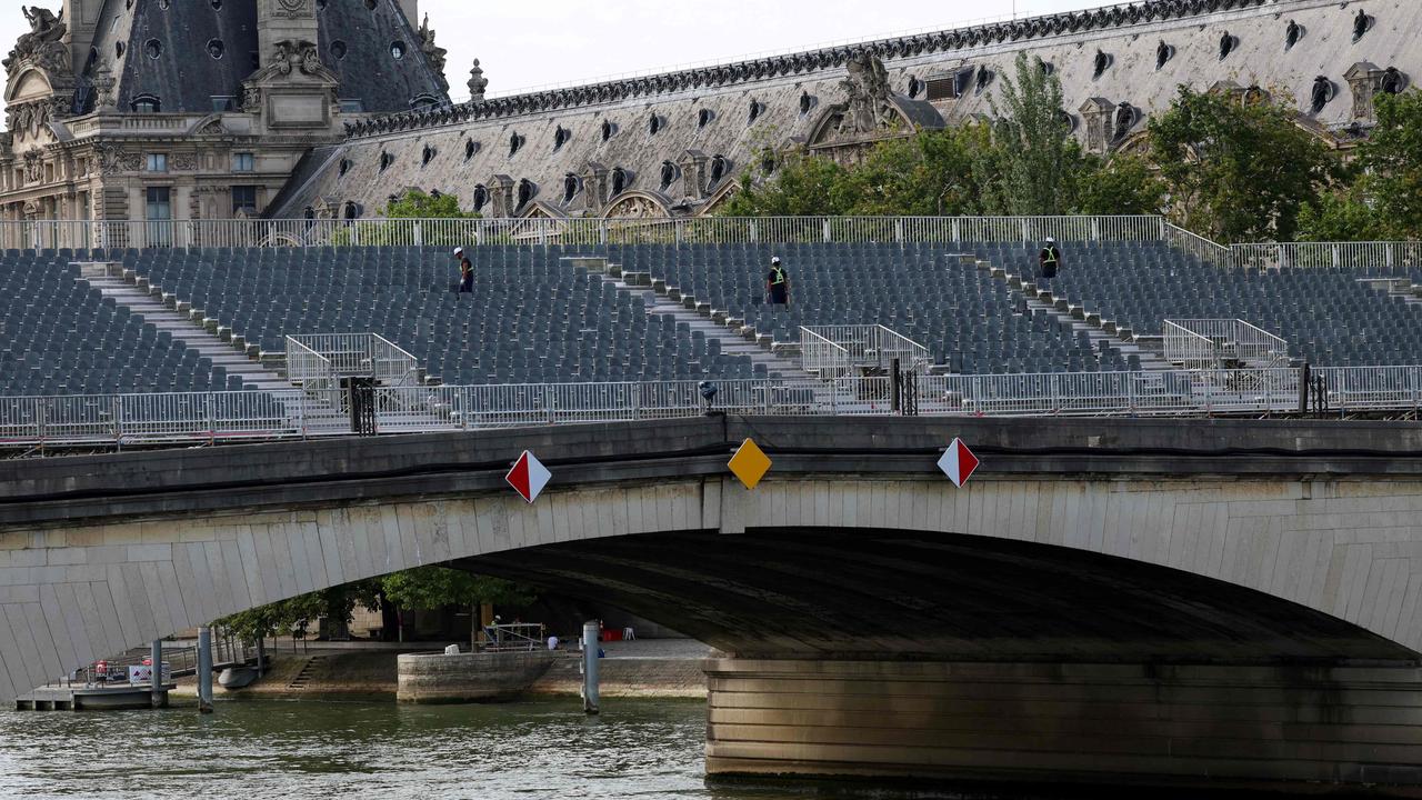 Workers inspect spectator stands on Pont du Carrousel over the River Seine. Picture: EMMANUEL DUNAND / AFP.