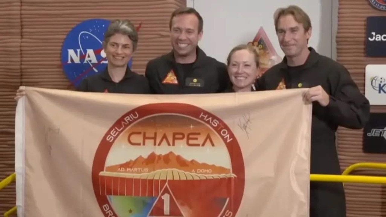 From left to right, Anca Selariu, Nathan Jones, Kelly Haston, and Ross Brockwell, held up the mission’s flag moments before entering the habitat until July 2024. Picture: YouTube/ NASA