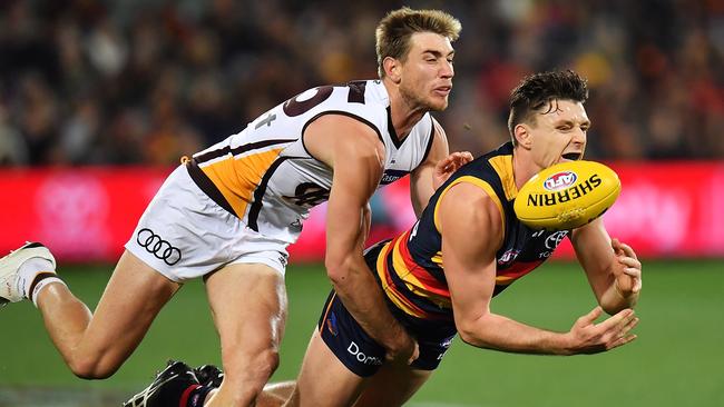 Jake Lever handballs as he is tackled by Ryan Schoenmakers during their round 14 clash at Adelaide Oval.