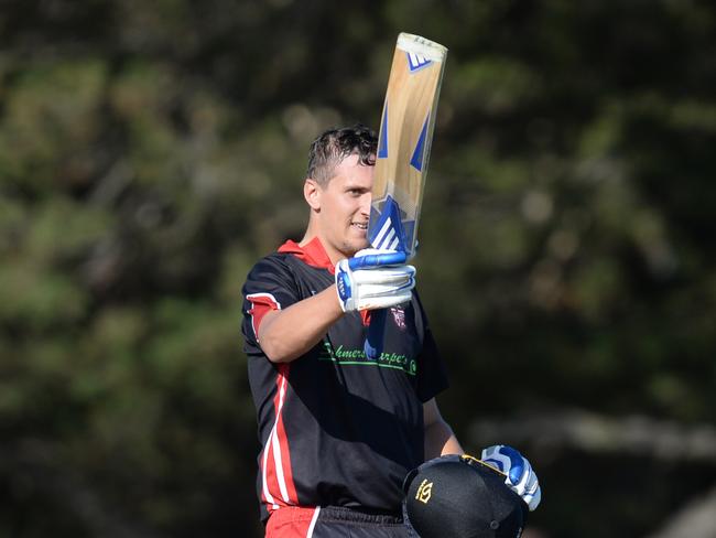 South Caulfield’s Brad Erasmus raises his bat after reaching his century against McKinnon.