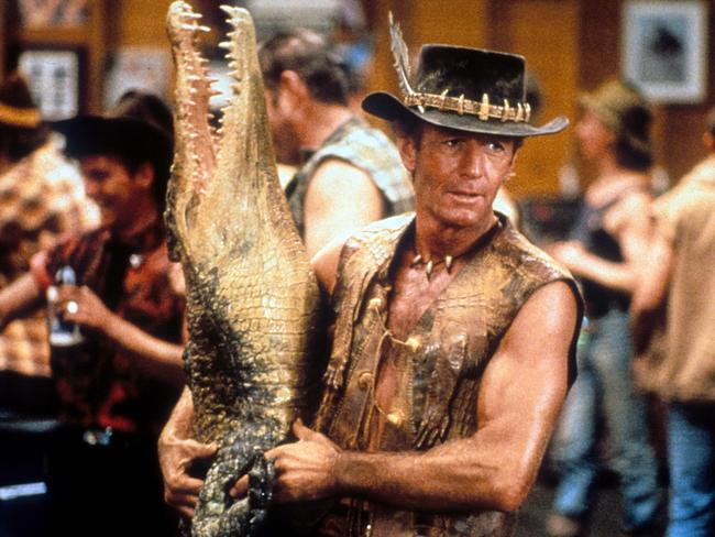 Paul Hogan carrying dead crocodile in bar in a scene from the film 'Crocodile Dundee', 1986. (Photo by Paramount/Getty Images)