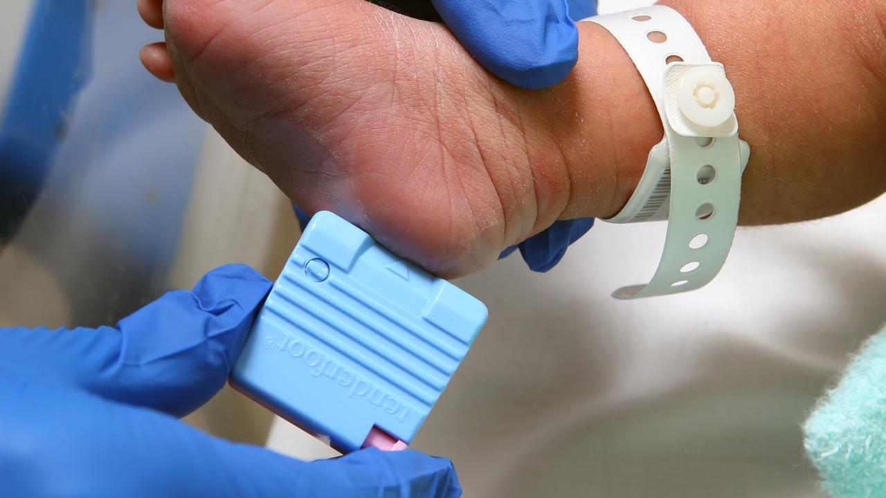 A newborn receives a standard heel prick test.