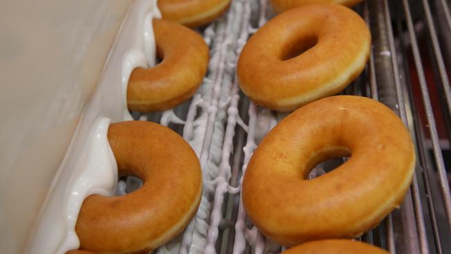 Krispy Kreme doughnuts go through the glaze fountain. Picture: Carmela Roche