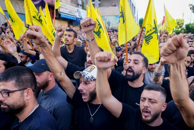 Mourners, some waving Hezbollah flags, attend the funeral of group members killed in an Israeli strike on Beirut