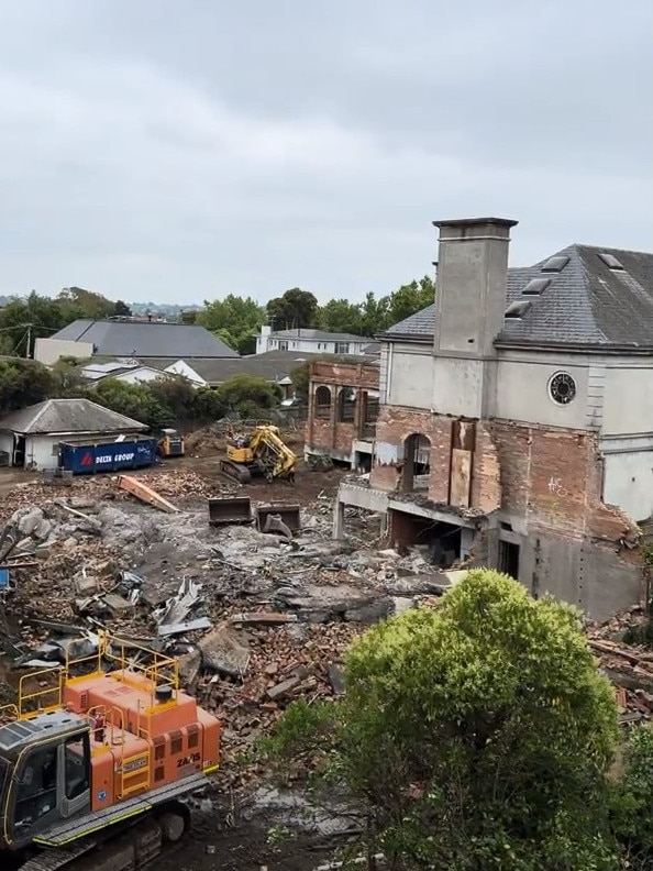 Construction shows excavators demolishing parts of the red brick mansion.