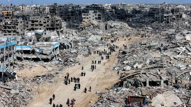 People walk past rubble of collapsed buildings near a destroyed clinic of the United Nations Relief and Works Agency for Palestine Refugees at the Jabalia camp for Palestinian refugees in the northern Gaza Strip on January 19. Picture: Omar Al-Qattaa/AFP