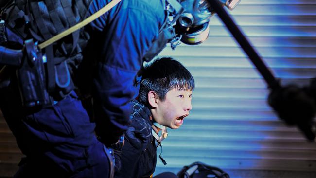 A pro-democracy protester is held by police outside Tsim Sha Tsui Police station in Hong Kong.