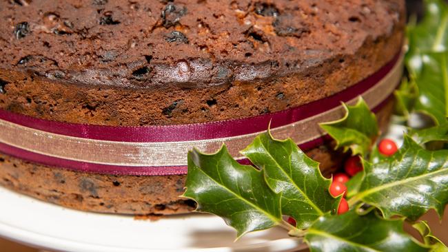 A whole delicious fruit Christmas cake surrounded by holly
