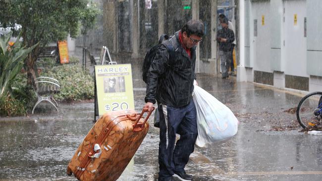 One man carries his belongings out of Mascot Towers and into the rain. Picture: David Swift