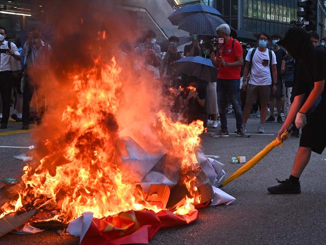 (FILES) This file photo taken on October 4, 2019 shows a protester holding a yellow umbrella, as a banner which celebrates the 70th anniversary of China's founding is burned, during a protest in the Central district in Hong Kong. - Long dubbed the Chinese-language "Oscars", the Golden Horse Film Awards will kick off in Taipei on November 27, 2021 -- again without the legion of Chinese filmmakers and stars who once used to walk the red carpet. This year two Hong Kong films that explore the city's 2019 pro-democracy protests, as well as one Chinese documentary about Tibet are nominated. (Photo by Philip FONG / AFP) / TO GO WITH Taiwan-film-festival-politics-China-HongKong,FOCUS by Amber Wang, Holmes Chan and Su Xinqi