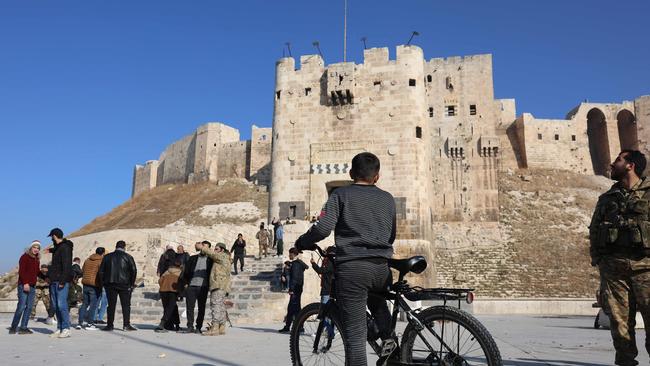 Anti-government fighters and residents gather in front of the landmark citadel of Aleppo, after jihadists and their allies entered the northern Syrian city, on November 30. Picture: Mohammed Al-Rifai/AFP