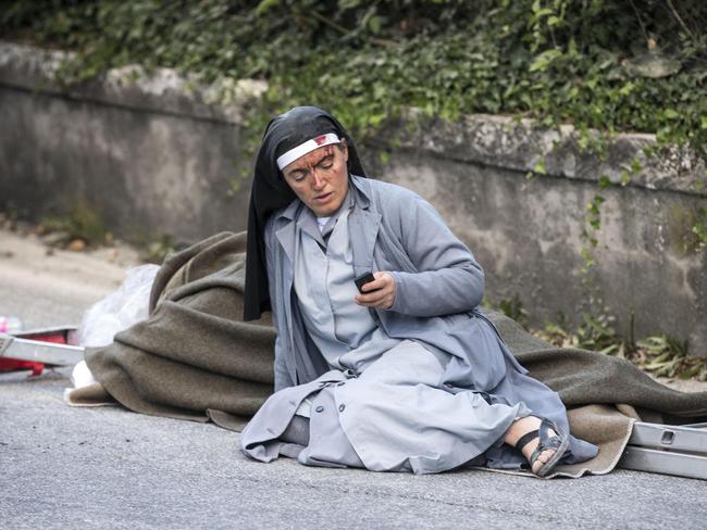 A nun checks her mobile phone after the quake in Amatrice as rescuers scramble for survivors. Picture: Massimo Percossi/ANSA