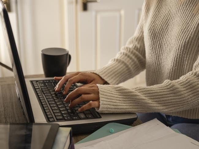 An unrecognisable young woman using her laptop and completing some work at home in Northumberland, North East England.