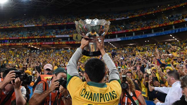 Australia's Tim Cahill lifts the AFC Asian Cup football trophy to the crowd.