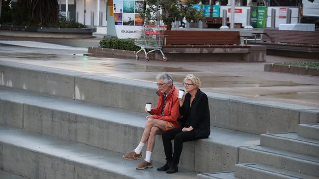 Surfers Paradise wakes up to its first day in lockdown due to the latest CoVid-19 scare. Tradesman still at work at Paradise Centre. An elderly couple enjoy a coffee on their own. Picture Glenn Hampson