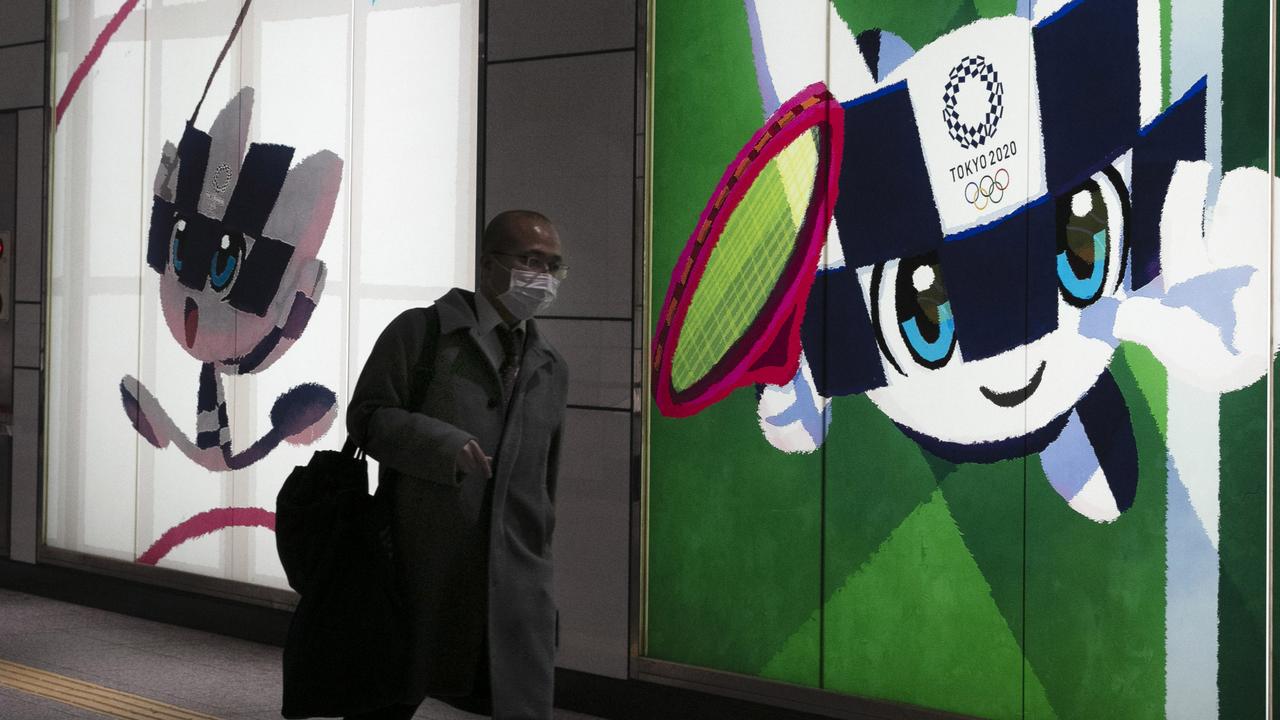 A man with a mask walks past large displays promoting the Tokyo 2020 Olympics in Tokyo. Picture: AP/Jae C. Hong