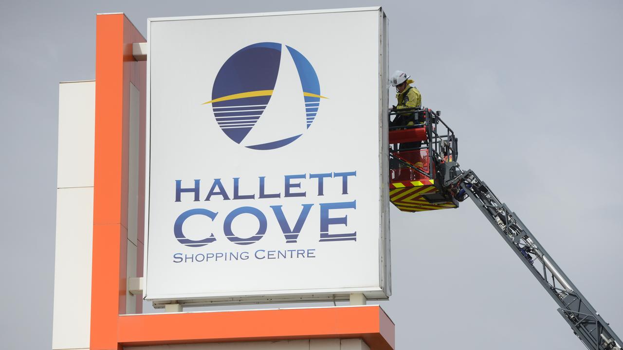 The MFS inspects the Hallett Cove Shopping Centre sign, which was damaged in the wind. Picture: AAP / Brenton Edwards