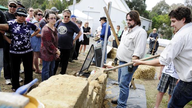 Onlookers learn how a mud brick wall is built at last year’s Practically Green Festival.