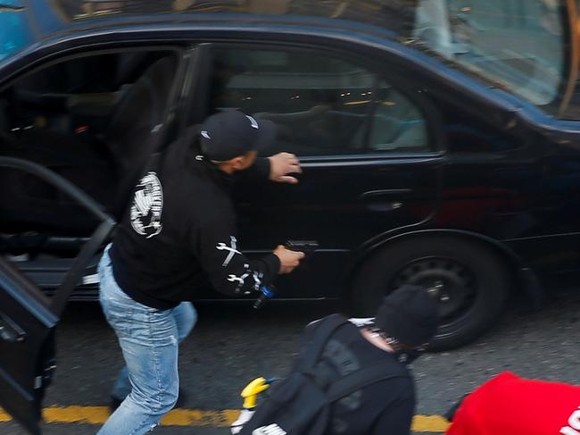 A man exits a vehicle with a gun as a man is tended to by medics after being shot by a driver who tried to drive through a protest against racial inequality in the aftermath of the death in Minneapolis police custody of George Floyd, in Seattle, Washington, U.S. June 7, 2020. REUTERS/Lindsey Wasson - RC2S4H920JZS