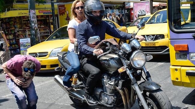 The ‘maverick’ Varoufakis leaves the Ministry of Finance with his wife Danai on the back of a motorbike downtown Athens after resigning in a bid to appease creditors.