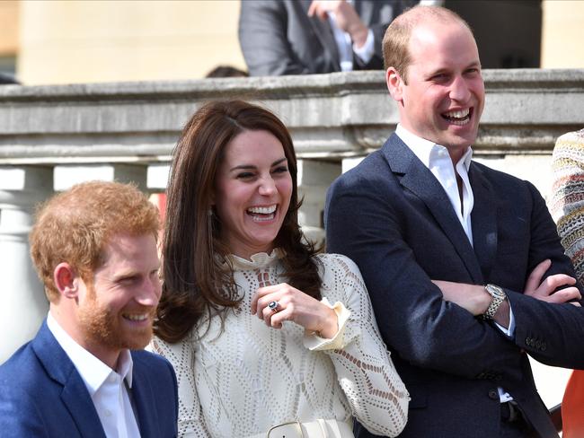 Prince Harry, Catherine, Duchess of Cambridge and Prince William, Duke of Cambridge, laugh as they host a tea party in the grounds of Buckingham Palace. Picture: Andrew Parsons.