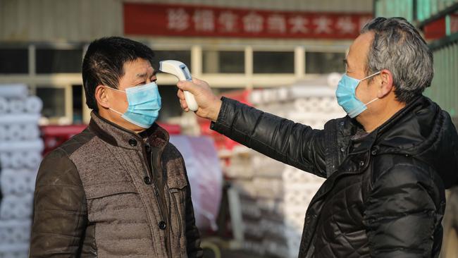 A worker checks the body temperature of a colleague at a textile factory in Hangzhou, in China's eastern Zhejiang province. Picture: AFP