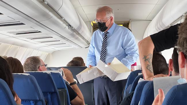 Scott Morrison hands out sweet treats on the media plane after a water leak grounded his plane. Picture: Jason Edwards