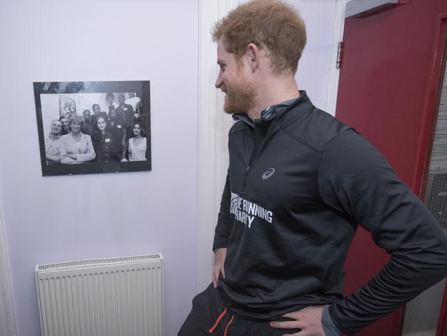 Prince Harry looks at a photograph of his mother Princess Diana, during a visit to The Running Charity, which is the UK's first running-orientated program for homeless and vulnerable young people. Picture: Getty