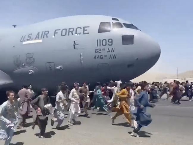 People run on tarmac of Kabul international airport as a US military aircraft attempts to take off in this still from a video. Picture: Supplied