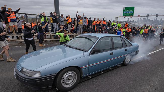 A car does a burnout in front of protesters. Picture: Jason Edwards
