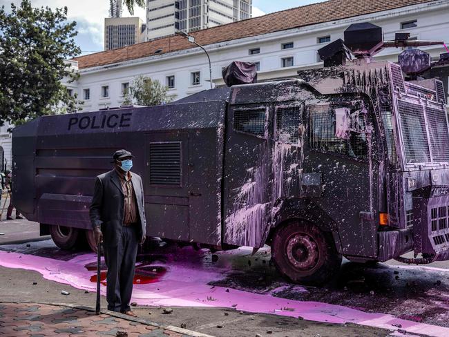 EDITORS NOTE: Graphic content / TOPSHOT - A man stands next to a Kenya Police water cannon truck full of paint thrown by protesters during a nationwide strike to protest against tax hikes and the Finance Bill 2024 in downtown Nairobi, on June 25, 2024. Kenya's President William Ruto vowed to take a tough line against "violence and anarchy" on Tuesday after protests against his government's proposed tax hikes turned deadly and demonstrators ransacked parliament. Kenyan police shot dead one protester near the country's parliament Tuesday, a rights watchdog said as demonstrators angry over proposed tax hikes breached barricades and entered the government complex, where a fire erupted. The mainly Gen-Z-led rallies, which began last week, have taken President William Ruto's government by surprise, with the Kenyan leader saying over the weekend that he was ready to speak to the protesters. (Photo by LUIS TATO / AFP)