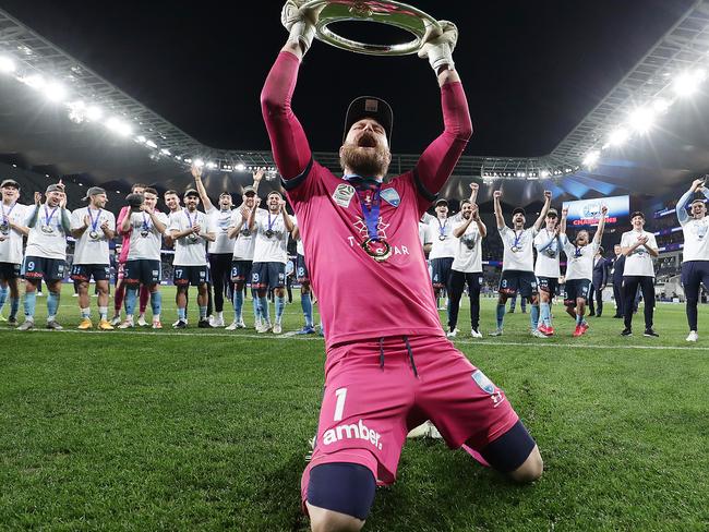 Andrew Redmayne celebrates with the A-League trophy.