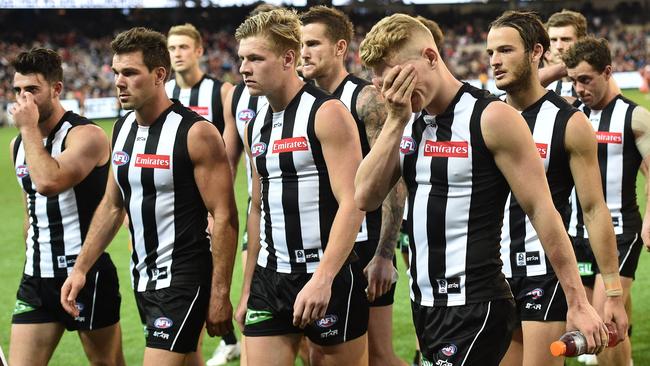 Adam Treloar (third from left) wipes his eyes as Magpies leave the ground. AAP Image/Julian Smith