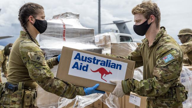 Royal Australian Flight Lieutenant Lachlan Connell (right) passes an Australian Aid box to Private Bianca Jordan at Honiara International Airport, Solomon Islands, last December.