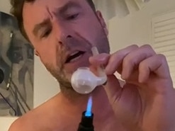 Geoff Bainbridge smoking a glass pipe and performing lewd acts in a bedroom.