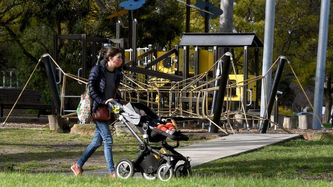 A woman and child pass a closed playground in Melbourne. Picture: William West