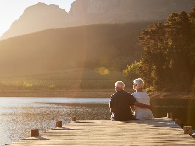 Romantic Senior Couple Sitting On Wooden Jetty By Lake